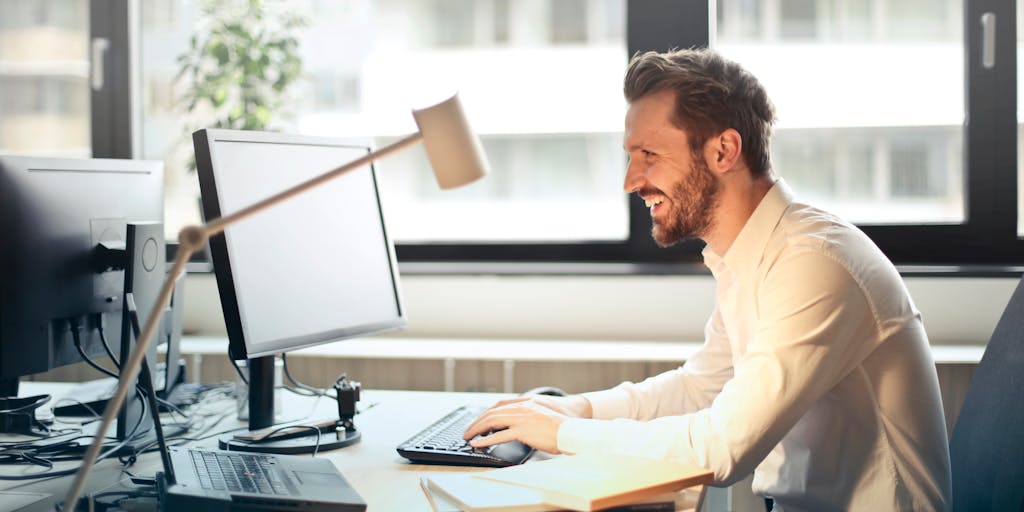 A person sitting at a desk, enthusiastically typing an email on their laptop, with a thought bubble above their head filled with icons representing backlinks, connections, and networking. This image captures the excitement and potential of successful outreach.