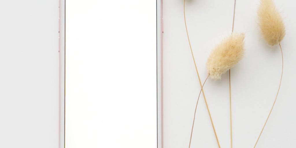 A creative flat lay of a smartphone displaying a prospect list app alongside a printed Excel template. Surrounding the devices are motivational quotes and a plant, symbolizing growth and networking.