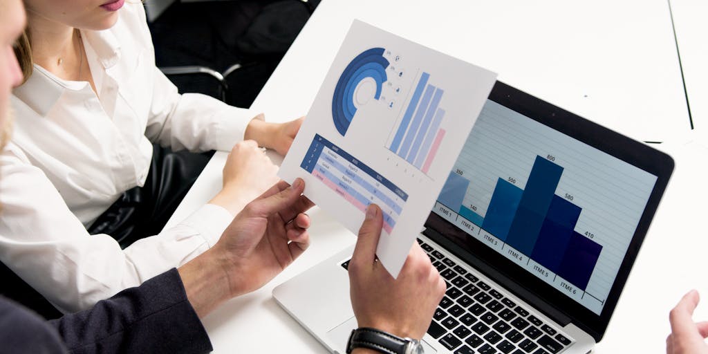 A close-up shot of a business professional analyzing a digital dashboard on a tablet, showcasing various KPIs like sales growth, customer acquisition cost, and conversion rates. The background features a modern office environment with charts and graphs on the walls, emphasizing a data-driven culture.