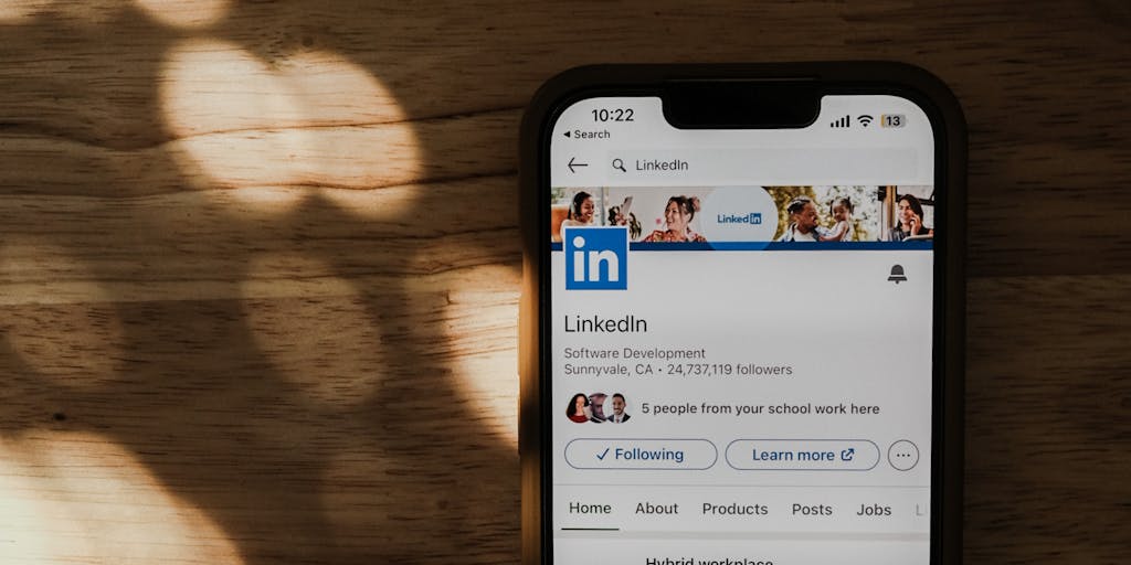 A close-up shot of a hand holding a smartphone displaying the LinkedIn app, with a visual overlay of a counter showing the number of connection requests sent. The background features a blurred office environment to emphasize a professional setting.