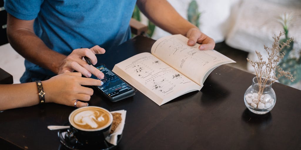 A close-up of a hand holding a coffee cup with a latte art heart, while the other hand is typing on a smartphone. The background is softly blurred, showcasing a café environment with people chatting and enjoying their drinks. This image captures the essence of modern communication and the casual nature of a coffee chat, perfect for an email template.