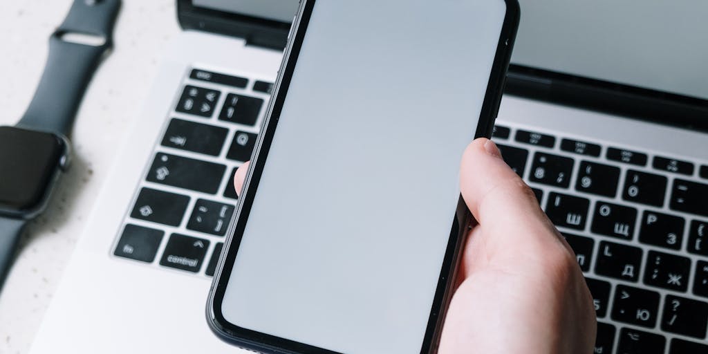 An overhead view of a person sitting at a desk, surrounded by sticky notes with networking tips and strategies. The person is holding a smartphone, looking at LinkedIn, with a focused expression, illustrating the effort put into crafting the perfect cold message.