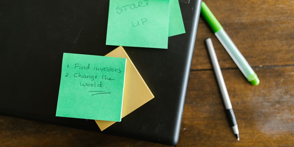 An overhead view of a desk with a laptop open to an Outlook email blast template. Surrounding the laptop are colorful sticky notes with tips for effective email marketing, such as 'Catchy Subject Line' and 'Call to Action'.