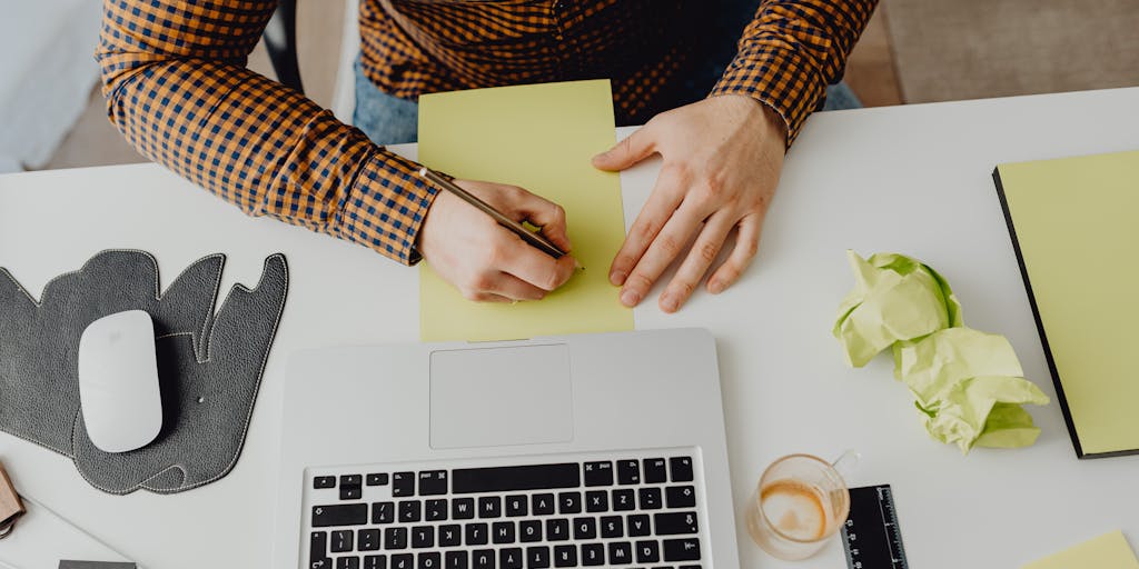 An office desk scene with a crumpled piece of paper that has 'We need to break up' written on it, alongside a coffee cup and a laptop. The setting conveys a casual yet serious tone, highlighting the personal touch in a sales break-up email.