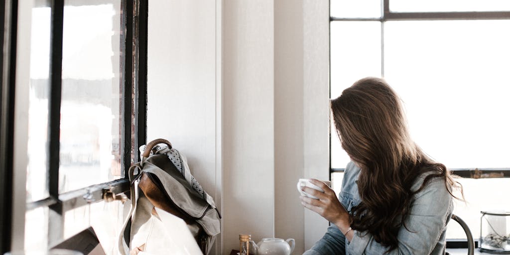 A person sitting at a café, looking contemplative while typing on a laptop. The screen shows a partially written break-up email, and a coffee cup sits beside them. This captures the moment of decision-making in a sales relationship.
