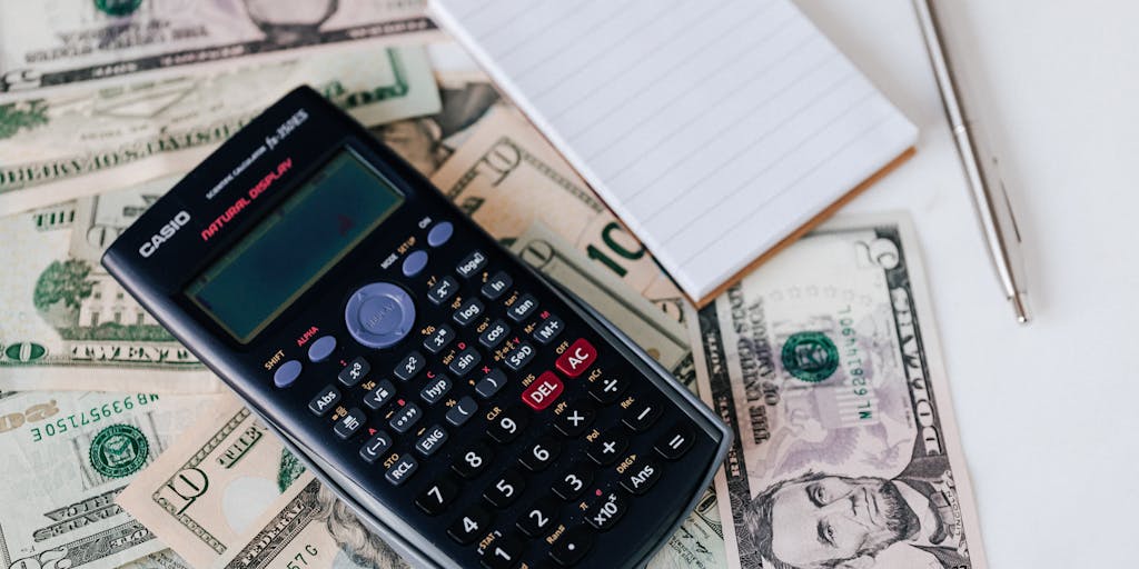 A close-up shot of a calculator with a notepad beside it, where the notepad has handwritten notes about outreach costs, such as 'email campaigns', 'social media ads', and 'influencer partnerships'. The background is slightly blurred to emphasize the calculator and notes.
