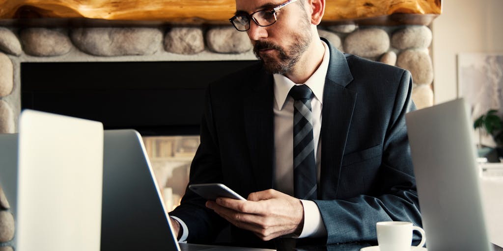 An overhead view of a desk with a laptop open to the Salesloft pricing page, alongside a cup of coffee, a notepad with handwritten notes, and a smartphone displaying a sales app. The scene should evoke a sense of productivity and focus on pricing strategies.