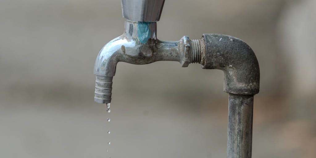 A close-up shot of a dripping faucet with coins falling from the spout instead of water, symbolizing the concept of pricing and value. The background is softly blurred to emphasize the faucet and coins, creating a striking visual metaphor for financial flow.