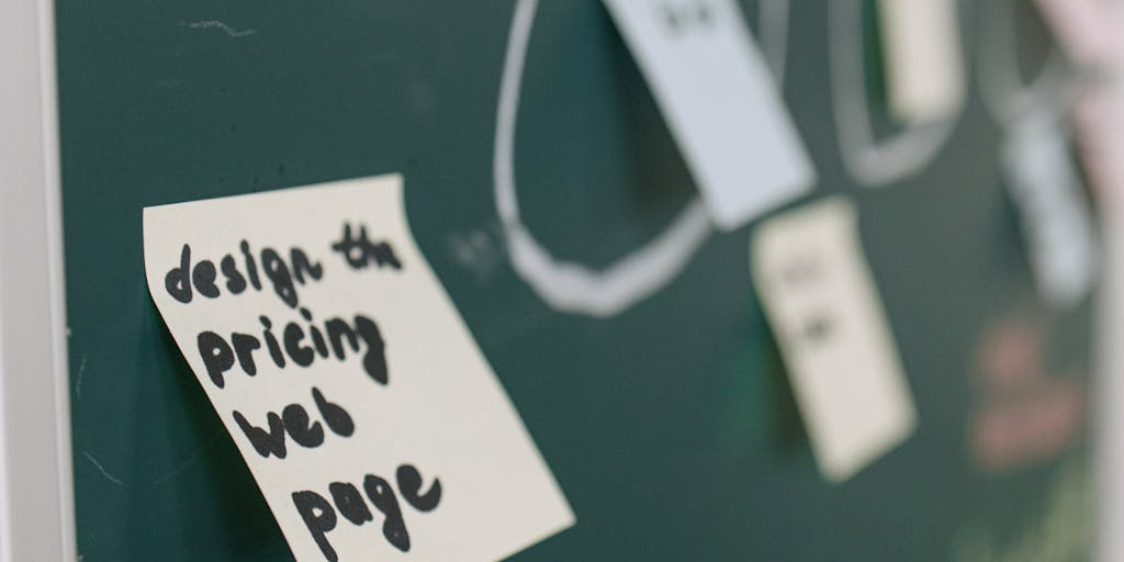 A creative flat lay of a pricing strategy brainstorming session, featuring a whiteboard with pricing models sketched out, colorful markers, and a smartphone displaying the Sales Loft app. The image should convey a sense of collaboration and innovation.