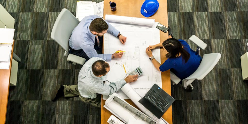 A dynamic image of a team meeting in a modern conference room, with a large screen displaying Sales Loft pricing options. Team members are engaged in discussion, pointing at the screen, showcasing teamwork and strategic planning.