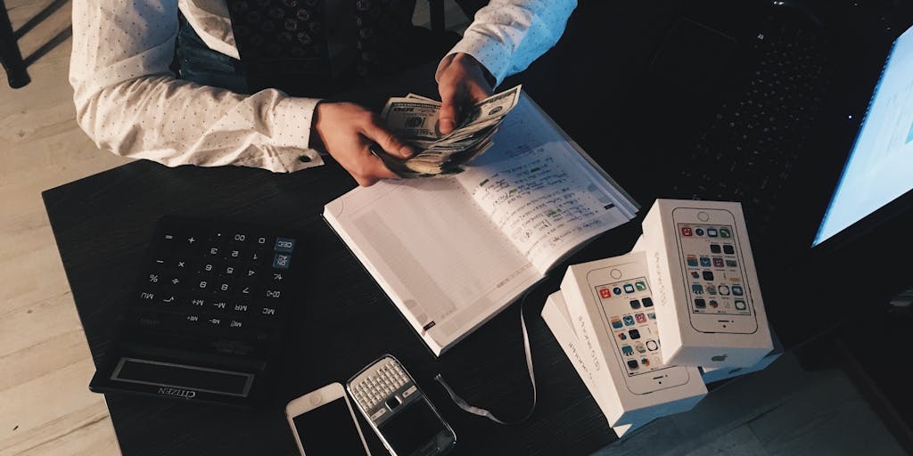 An overhead view of a desk cluttered with various pricing documents, a laptop with an email draft open, and a clock showing the time. The image captures the urgency of sending pricing information instantly, with a hand reaching for the laptop keyboard.