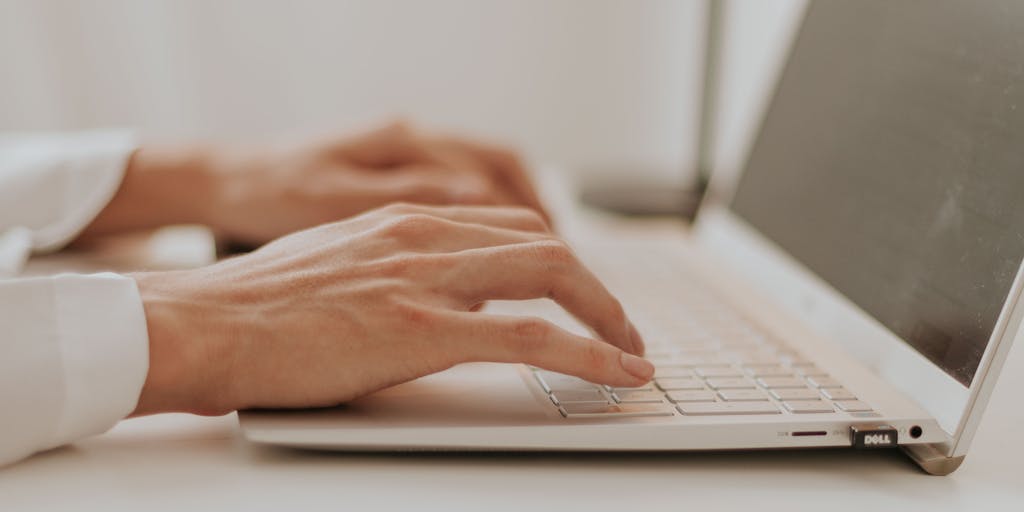 A close-up shot of a computer screen displaying a colorful and engaging pricing table for Yet Another Mail Merge, with a hand pointing at the most popular plan. The background should be a cozy home office setting, with a coffee cup and stationery items to create a warm atmosphere.