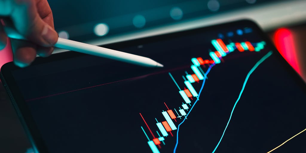 A close-up shot of a digital tablet displaying a colorful graph with fluctuating lines and numbers, symbolizing dynamic pricing strategies. The background features a blurred office setting with a person analyzing data, emphasizing the analytical aspect of Pipl Pricing.