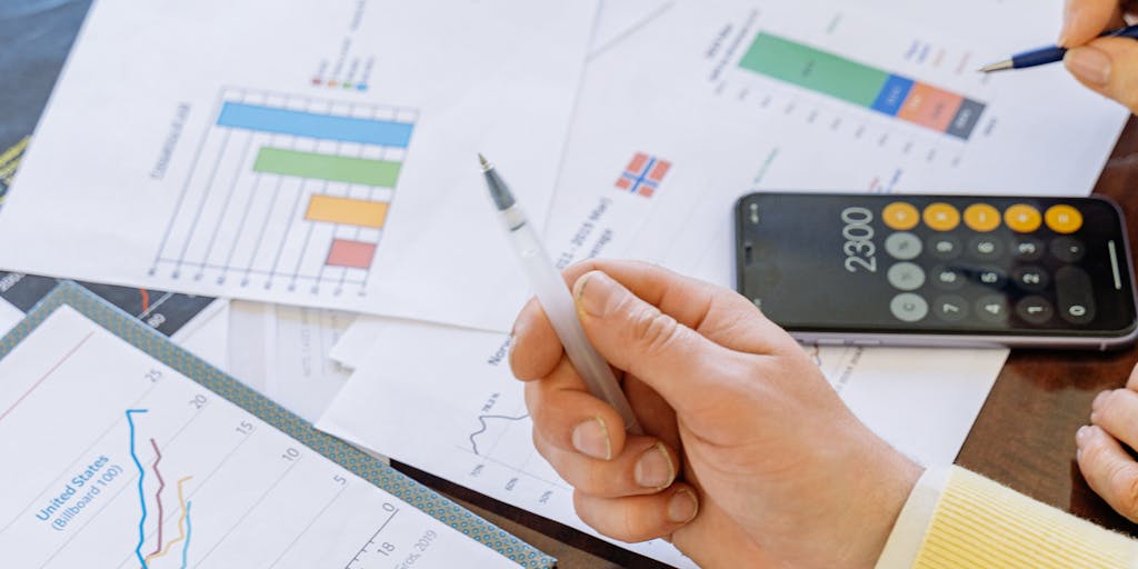 A close-up shot of a calculator with a hand pressing buttons, surrounded by charts and graphs that represent pricing strategies. The background should be slightly blurred to emphasize the calculator and the financial documents.