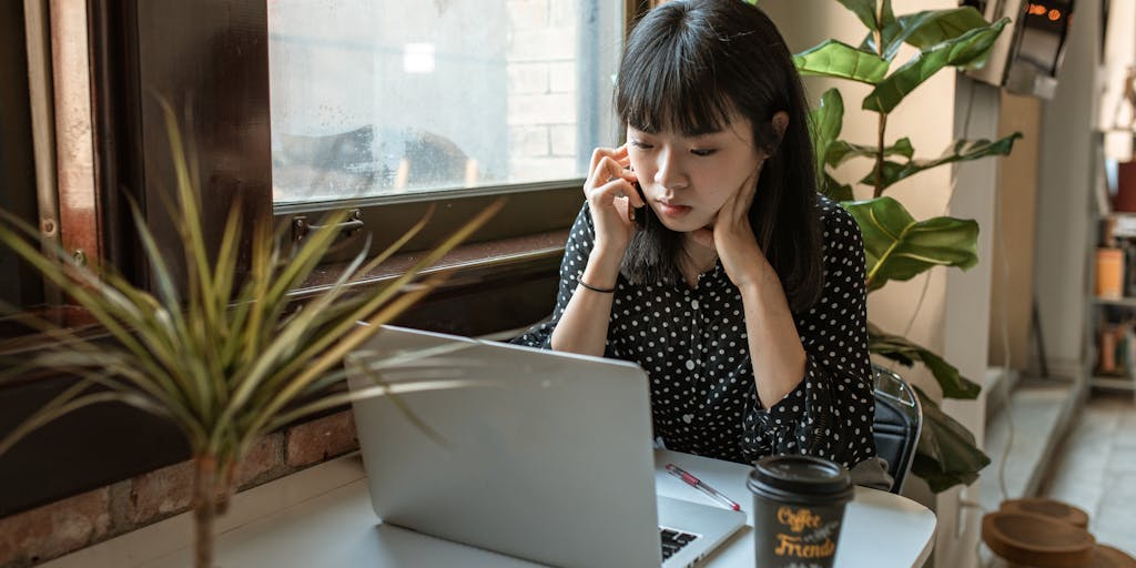 An overhead view of a workspace with a laptop open to the Adobe Marketo pricing page, alongside a cup of coffee, a notepad filled with marketing ideas, and a smartphone displaying a graph of marketing ROI. The composition should evoke a sense of planning and strategy.