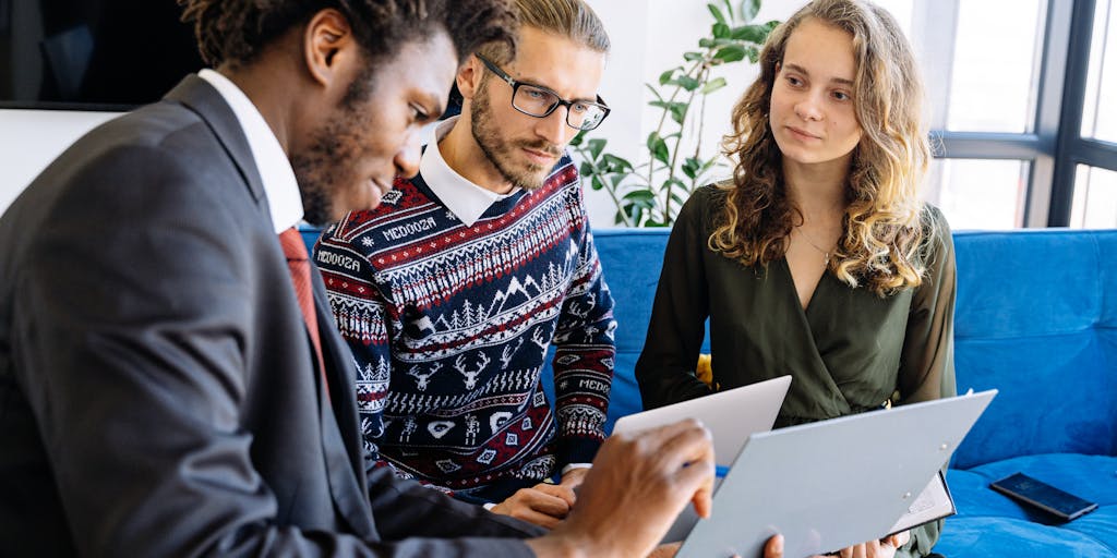 An overhead view of a diverse group of people sitting around a table, engaged in a brainstorming session. They are surrounded by sticky notes and charts related to customer pricing strategies. The image captures the collaborative spirit of developing pricing models tailored to customer needs.