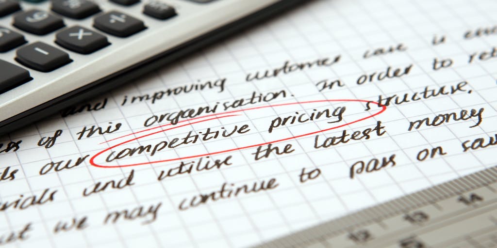 A creative flat lay of a calculator, notepad, and a cup of coffee, with handwritten notes on pricing strategies scattered around. The scene is set on a wooden desk, giving a warm and inviting feel to the analytical process of exact target pricing.