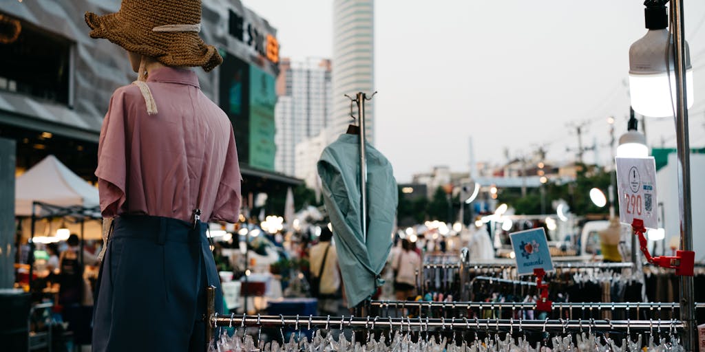 An overhead shot of a busy marketplace where vendors are displaying their products with various price tags. In the center, a large sign reads 'Merge Pricing' with arrows pointing to different stalls, illustrating the idea of combining prices for better deals. The vibrant colors of the products and tags create an eye-catching visual.