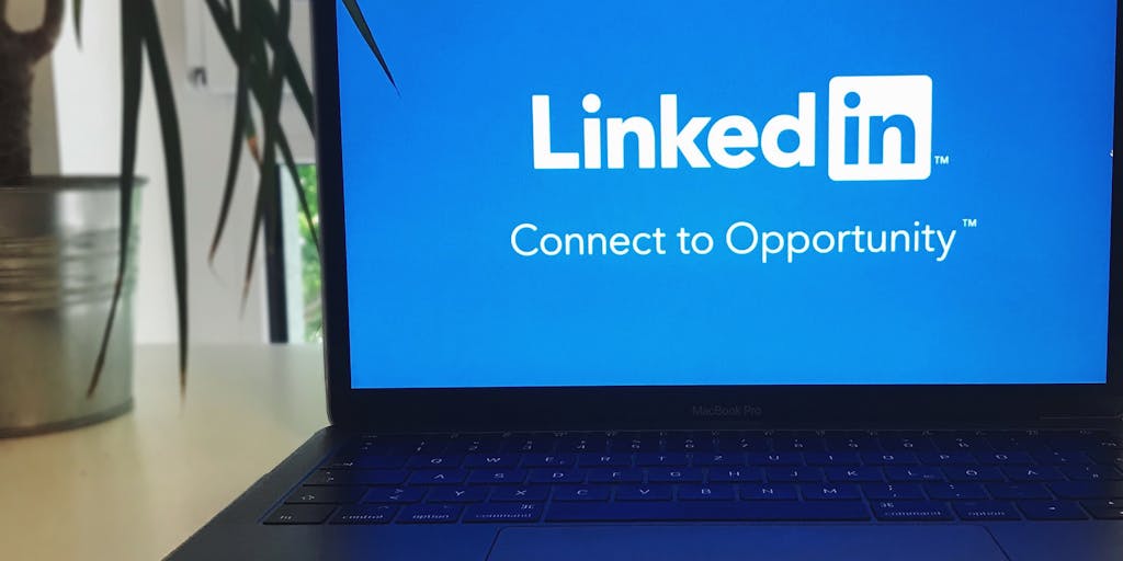 A close-up shot of a laptop screen displaying the LinkedIn interface, specifically highlighting the 'Pending Connections' section. The background features a cozy home office setup with a coffee cup and a notepad, symbolizing a professional yet relaxed environment.