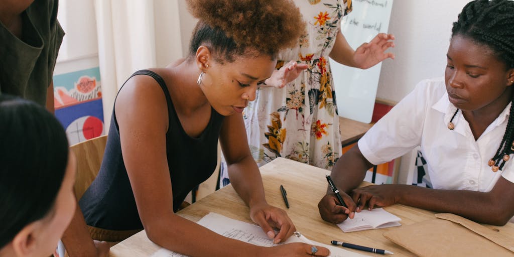 An overhead view of a diverse group of professionals gathered around a table, each with their devices open to LinkedIn. They are animatedly discussing potential candidates, with sticky notes and resumes scattered around, showcasing a collaborative recruiting environment.