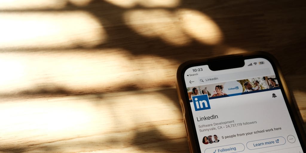 A close-up shot of a smartphone displaying the LinkedIn app with a notification for a new InMail message. The phone is held by a person in a business suit, with a blurred background of a bustling office environment, symbolizing the potential opportunities that come with LinkedIn Premium.