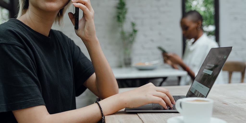 A person sitting at a café with multiple devices (tablet, smartphone, laptop) open to different LinkedIn accounts. The individual is multitasking, with a coffee cup beside them, showcasing the flexibility and modern approach to managing multiple profiles.