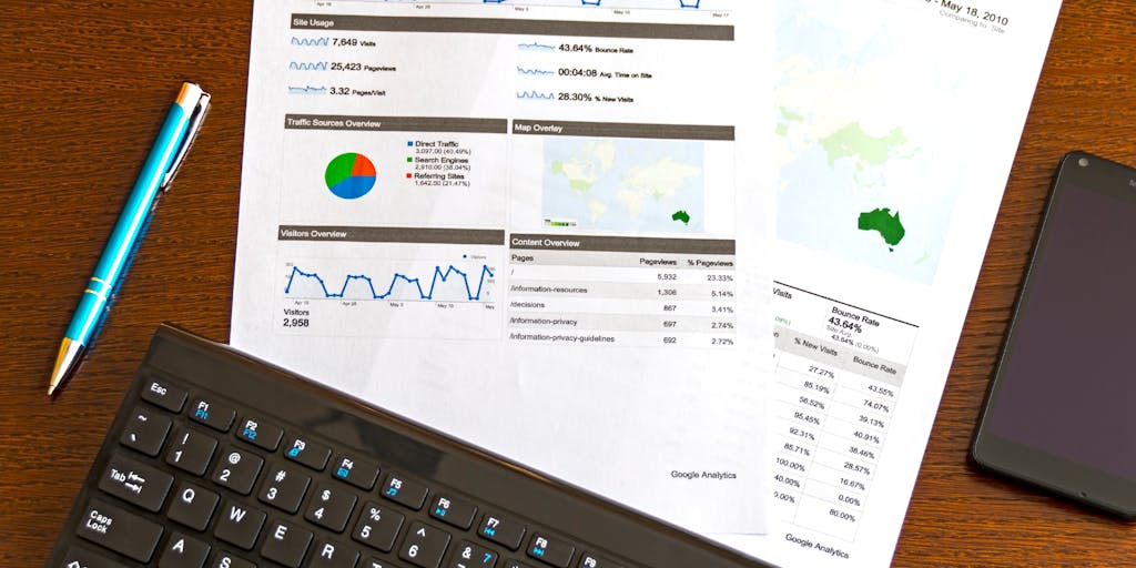 A close-up shot of a computer screen displaying a colorful dashboard filled with graphs, charts, and data visualizations. The screen is surrounded by various data enrichment tools like sticky notes, books, and a coffee cup, symbolizing the analytical process.