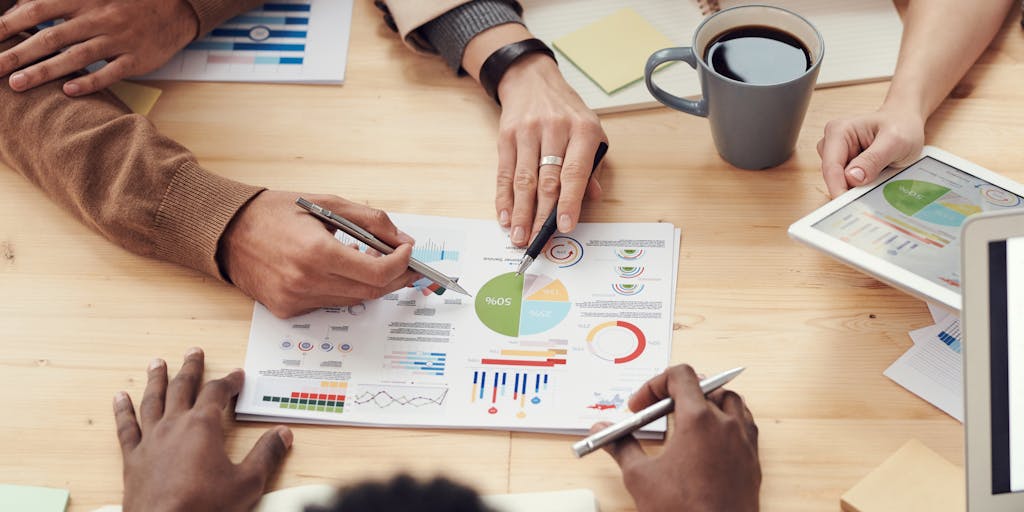 A team of diverse professionals gathered around a table, collaborating on a project with laptops open and data charts projected on a screen. The atmosphere is dynamic, showcasing teamwork in utilizing data enrichment tools to drive insights.