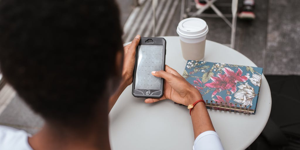 A close-up shot of a smartphone displaying a LinkedIn InMail message on the screen, with a blurred background of a busy coffee shop. The focus is on the phone, highlighting the digital communication aspect of networking.