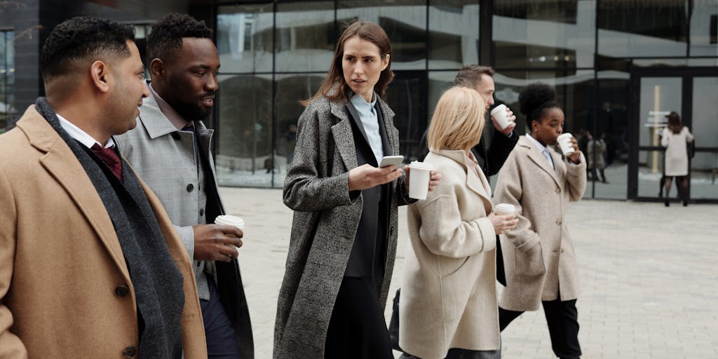 A group of diverse individuals gathered in a cozy coffee shop, each working on their laptops or discussing job opportunities. One person is holding a sign that says 'Open to Work' while others are engaged in conversation, showcasing collaboration and networking in the job search.