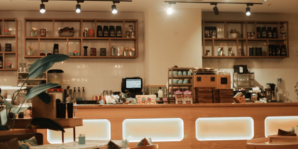 A vibrant coffee shop scene where two professionals are engaged in a lively conversation over coffee, with their laptops open displaying LinkedIn profiles. The background features a chalkboard with networking tips written on it, emphasizing the theme of connection and collaboration.