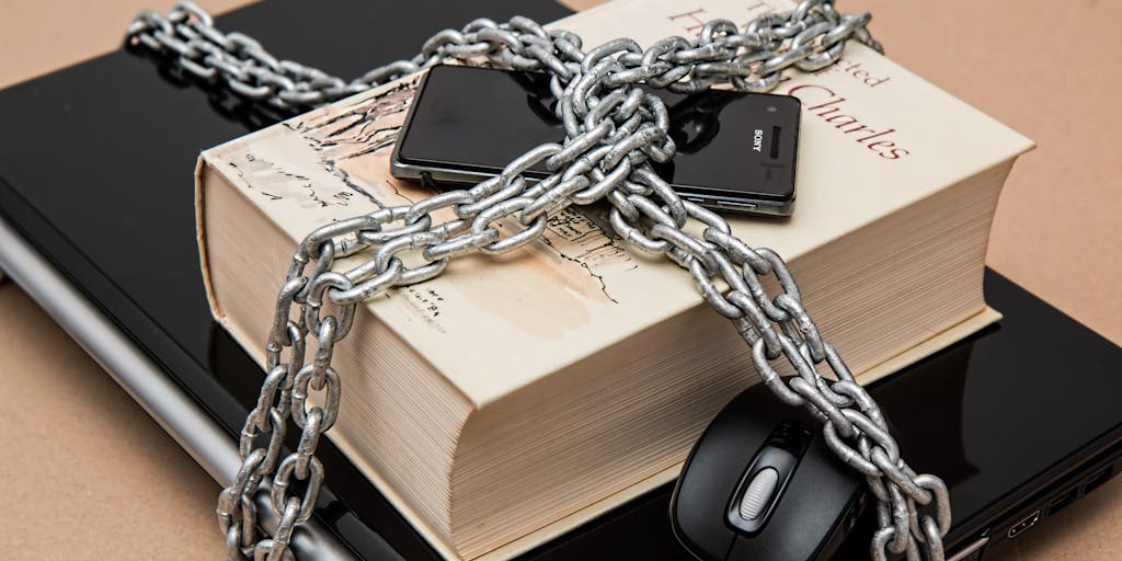 A close-up shot of a smartphone displaying the LinkedIn app with a 'Restricted Access' message, surrounded by chains and padlocks. The image conveys the feeling of being locked out of professional opportunities, highlighting the impact of social media restrictions.