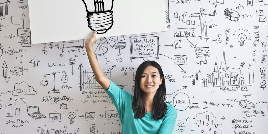 A person standing in front of a large whiteboard filled with a mind map of potential clients and strategies. The individual is pointing at a specific prospect, showcasing the brainstorming process.