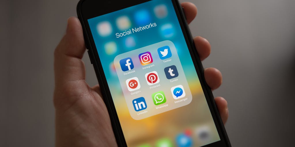 A close-up shot of a hand holding a smartphone displaying a LinkedIn app interface, with a notification pop-up that reads 'Invitation Withdrawn'. The background is a blurred office setting, symbolizing the professional environment of LinkedIn.