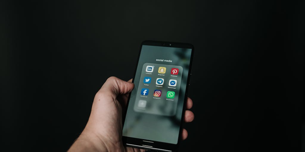 A close-up shot of a smartphone displaying a LinkedIn message interface, with a hand poised to hit 'send'. The background features a blurred image of a networking event, capturing the essence of connection and follow-up.