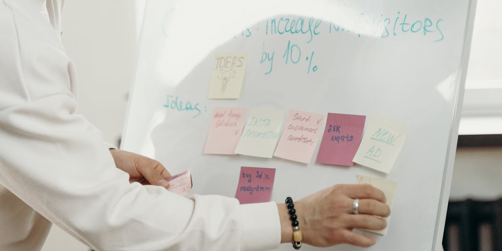 An overhead view of a diverse group of professionals gathered around a table, engaged in a brainstorming session. Sticky notes with names and roles are scattered across the table, representing the process of identifying decision-makers within a company.