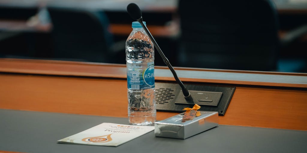 A close-up shot of a conference table with various seating arrangements, each seat labeled with different pricing tiers. The focus is on a digital tablet displaying a pricing chart, with a blurred background of a team discussing outreach strategies.