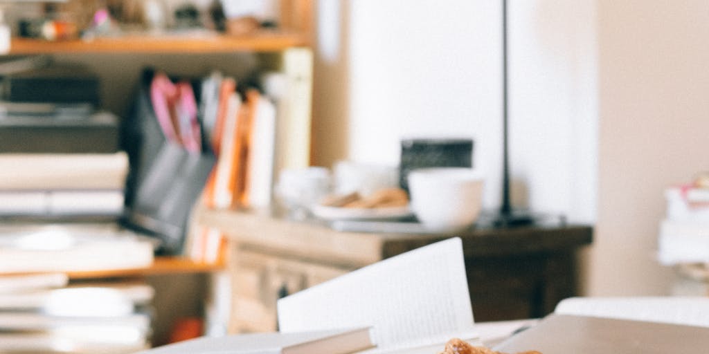 An overhead shot of a desk with a laptop open to the PieSync pricing page, surrounded by various pie ingredients (flour, sugar, fruits) and a notepad with pricing notes. This setup conveys the idea of 'baking' the perfect pricing strategy.